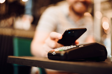 Close up details of wireless payment, customer using mobile phone, device with nfc technology for paying the bill