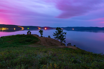Beautiful long exposure landscape view of the mountain lake Turgoyak, Russia with purple sky and summer house on the hill in summer night