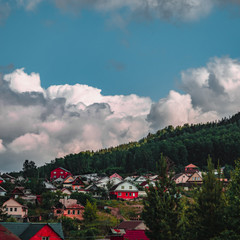Dramatic scenic view of mountain village with clouds rise above the forest