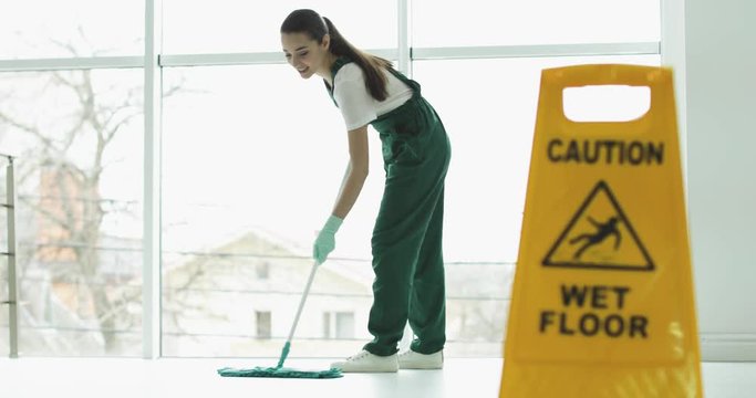Professional janitor cleaning floor with mop indoors