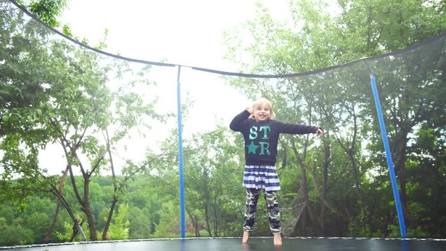 Girl jumping on a trampoline that stands in the park among the trees