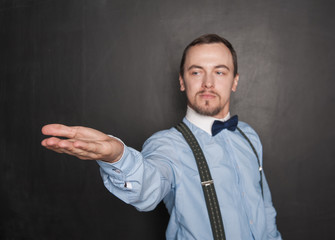 Handsome man showing on something on his hand on blackboard