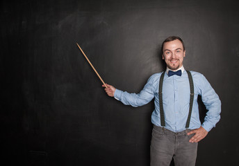 Smiling happy teacher man with pointer on blackboard