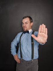Handsome business man with stop gesture on blackboard