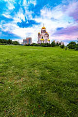 Wide angled view of the church Temple On The Blood in Yekaterinburg, Russia with beautiful cloudy sky and green grass on the foreground