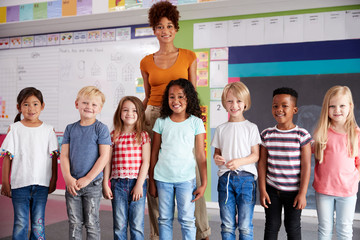Portrait Of Elementary School Pupils Standing In Classroom With Female Teacher