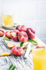 Reife und saftige Pfirsiche auf dem hellem tisch mit frischem Saft im Hintergrund