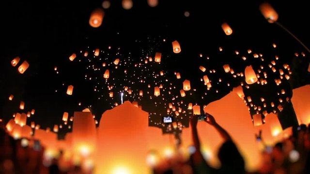 Time-lapse, Lanterns of light is released into the night sky by multi ethnic crowd. Celebrate lantern festival of light in Yeepeng festive at Chiangmai, Thailand. Low angle, wide shot, tilt-shift.