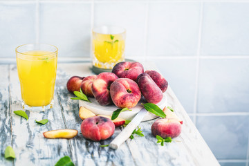 Reife und saftige Pfirsiche auf dem hellem tisch mit frischem Saft im Hintergrund