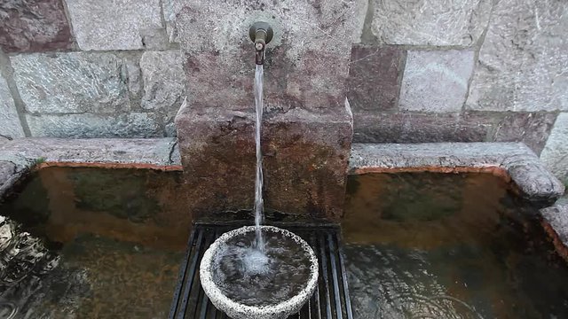 Agua de Fuente cayendo sobre una Taza de Piedra