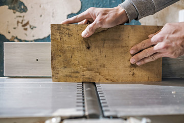 Fototapeta na wymiar Caucasian man making wooden parts for custom furniture on machine tool called thickness planer in carpentry. Producing lumber concept