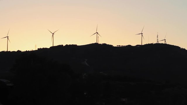 Silueta de Aerogeneradores sobre una colina, a contraluz,  con fondo de cielo de atardecer o puesta de sol Proyecto sin t&iacute;tulo