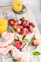 Reife und saftige Pfirsiche auf dem hellem tisch mit frischem Saft im Hintergrund