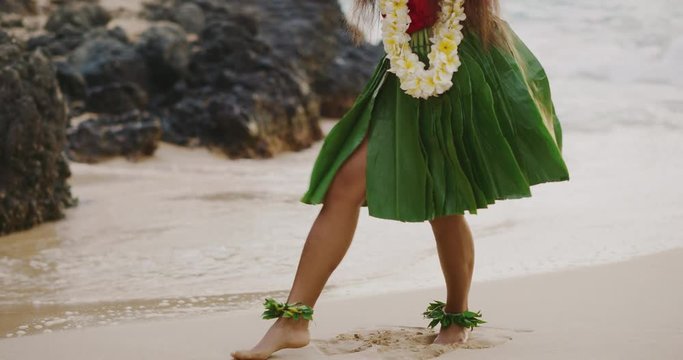 Shot of a Hula dancer's legs with a ti leaf skirt and ankle haku lei's, Hawaiian island hula dancing on the beach in slow motion