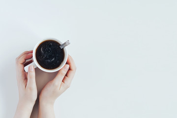 Woman hands hold a mug of black coffee. Top view with copy space.