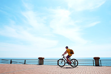 Young man with fit body riding the mtb mountain bike on sandy beach with beautiful azure water sea...