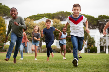 Excited Elementary School Pupils Running Across Field At Break Time