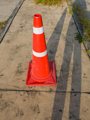 traffic cone, with white and orange stripes on gray asphalt, copy space