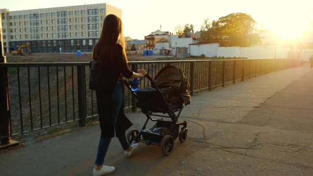 A girl with a black stroller walks through the city