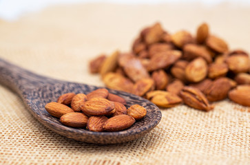 Almonds on a spoon wood with background texture.