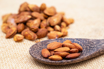 Almonds on a spoon wood with background texture.