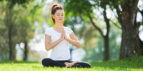 Yoga outdoor. Happy woman doing yoga exercises, meditate in the park. Yoga meditation in nature. Concept of healthy lifestyle and relaxation. Pretty woman practicing yoga on the grass - 277900750