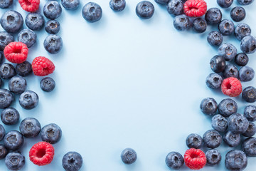 Frame made of blueberries and rapberries on blue background