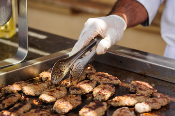 Cutlets frying on pan. Hands in gloves.