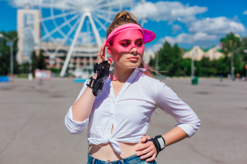 Portrait of an emotional girl in a pink cap visor and protective gloves for rollerblades and...