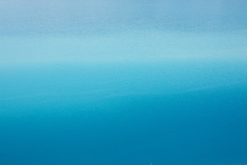 Background azure blue expanse of the sea with small ripples on the water. Transition from light blue to dark blue