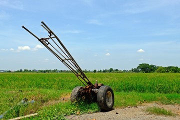 Idle walking tractor on rice field ready to be used at the beginning of rice growing season.	