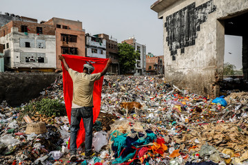 Rear view of rag picker separating cloth at landfill site