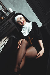 Sexy nun prays indoor . Beautiful young holy sister. Young beautiful nun with a cross in a robe in...