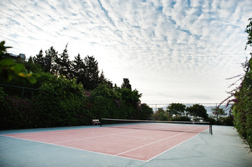 Empty tennis court resort with cloudy sky.