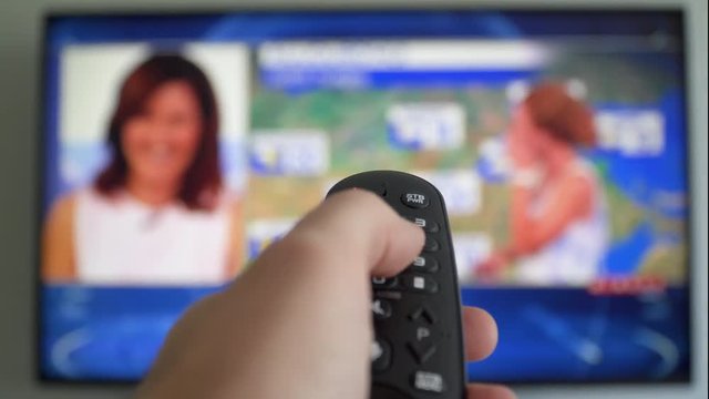 Fast switching the television news channels. Hand switches the channels by remote control Flat screen TV. Online video streaming service