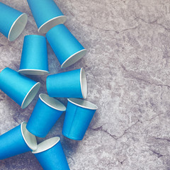 Blue paper disposable cups are on a stone background. Waiting for the festival, parties, events. Flat lay, top view minimal composition.