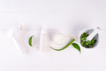 spa background with preparation handmade natural cosmetic products and face brush on white wooden background, flat lay