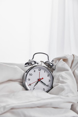 silver alarm clock in blanket in white bed