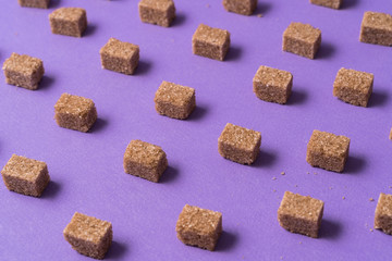 Minimalism style. Brown sugar cubes against purple background.