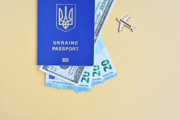 Biomedical Ukraine id passport with dollars and euro cash on yellow background, selective focus. Tourist trip concept with identity document, money and wooden airplane. Documents for business trip