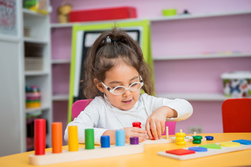 child girl with glasses for vision plays in educational classes