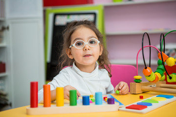 child girl with glasses for vision plays in educational classes