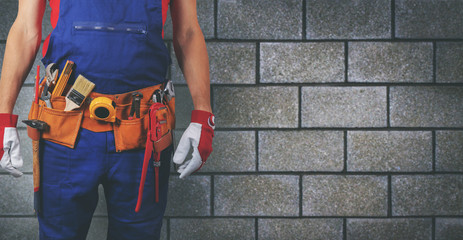 construction worker with tool belt on block wall background copy space