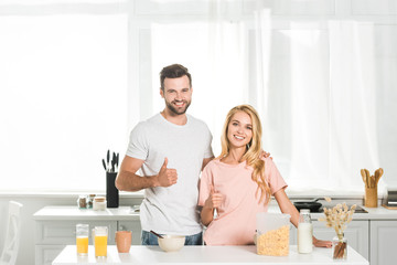 beautiful couple showing thumbs up during breakfast at kitchen