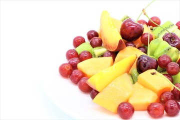 Fresh colorful fruit salad on a plate, white background, copy space on left