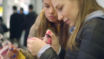 Pretty young women try new lipstick color on her hand in a cosmetics department