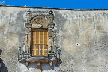 baroque mediterranean balcony with closed wooden shutters, a iron railing on a weathered stone wall