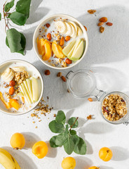 Granola bowl with fruits, nuts, milk and peanut butter in bowl on a white background. Healthy breakfast cereal top view