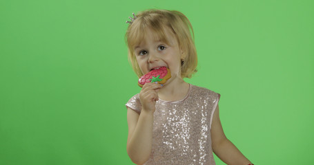 Girl in glossy dress begins to eat cookies in the form of strawberries