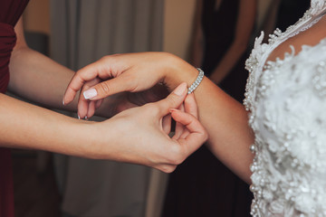 Obraz na płótnie Canvas Bride wearing a bracelet. Fees bride. girlfriend helps the bride